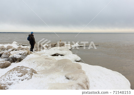 Man  standing on the ice near a freezing river 71548153