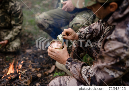 Picnic near Bonfire Hunter Opens Tin in Forest. Picnic near Bonfire Hunter Opens Tin in Forest. 71548423