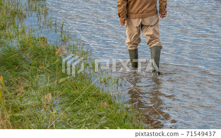 Unrecognizable person with rubber boots walking over the flood 71549437
