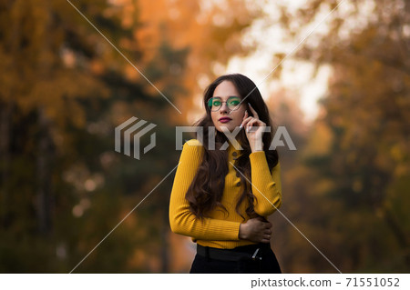 Charming young woman standing in autumnal park Charming young woman standing in autumnal park 71551052