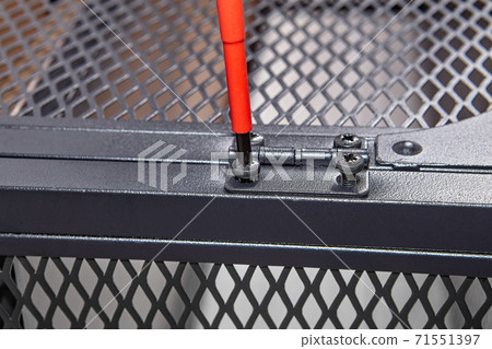 Handyman is tightening furniture door hinges with screwdriver while assembling TV stand. Handyman is tightening furniture door hinges with screwdriver while assembling TV stand. 71551397