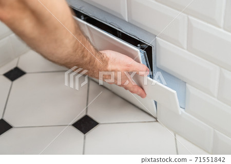 Open hidden revision sanitary hatch on the wall of tile under the bathroom 71551842