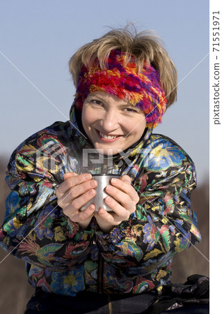 The young woman drinks a hot drink from a cup The young woman drinks a hot drink from a cup 71551971