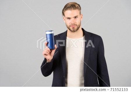 Man confident face holds shampoo bottle, grey background. Guy  71552133