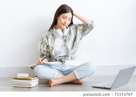 Beautiful Asian girl studying online at home Beautiful Asian girl studying online at home 71553767