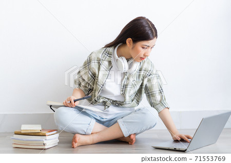 Beautiful Asian girl studying online at home Beautiful Asian girl studying online at home 71553769