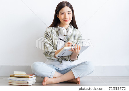 Beautiful Asian girl studying online at home Beautiful Asian girl studying online at home 71553772