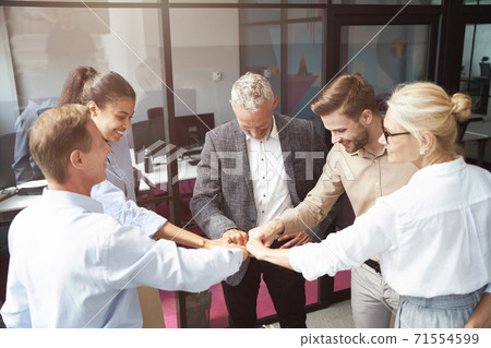 Celebrating success. Group of happy multiracial business people doing fists bump while standing in the office 71554599