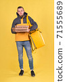 Food delivery smiling Caucasian young man in yellow jacket and with thermos bag on his shoulders on yellow background. Concept of Express food delivery in city, banner with space for text and slogan 71555689