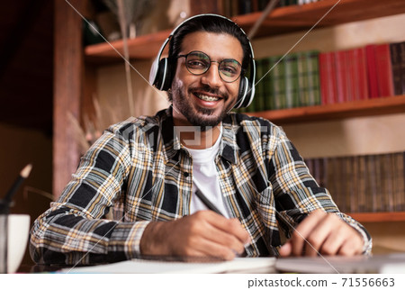 Portrait Of Happy Indian Student Sitting At Desk In Library Portrait Of Happy Indian Student Sitting At Desk In Library 71556663