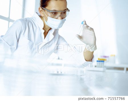 Female laboratory assistant analyzing a blood sample at hospital. Medicine, health care and researching concept 71557766
