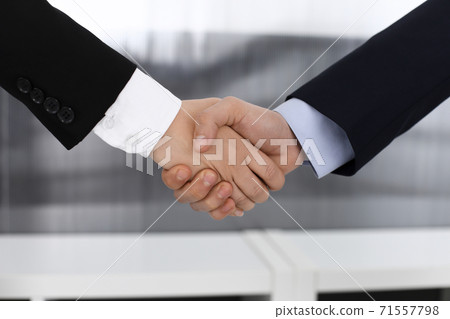 Businessman and woman shaking hands in office. Concept of handshake as success symbol in business 71557798