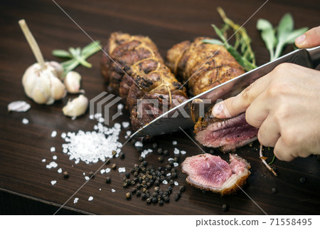 slicing organic roast beef roll on wood table with ingredients slicing organic roast beef roll on wood table with ingredients 71558495