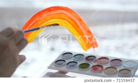 a woman's hand painting rainbow during Covid-19 quarantine at home. Stay at home Social media campaign for coronavirus prevention, let's all be well, hope during coronavirus pandemic concept 71559437