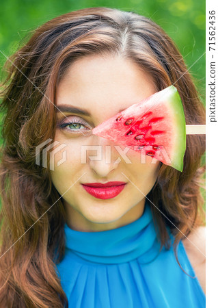 Woman covers eye with watermelon. Woman covers eye with watermelon. 71562436