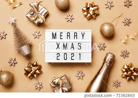 Lightbox with text MERRY XMAS 2021 and golden christmas decor on beige background. Creative layout in neutral monochrome colors 71562603