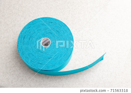 Blue adhesive elastic therapeutic kinesio tape on lying on table at doctor office. Kinesiology Injury rehabilitation, treatment and healthcare 71563318