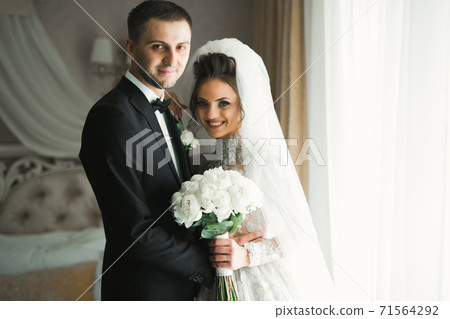 Romantic wedding moment, couple of newlyweds smiling portrait, bride and groom hugging 71564292