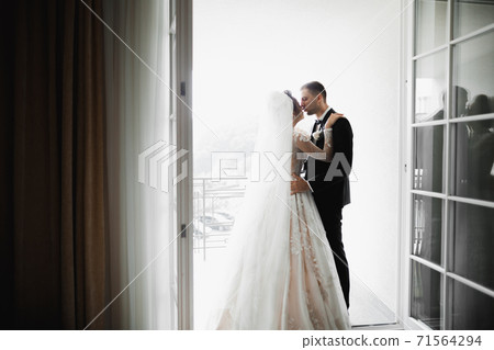 Beautiful bride and groom embracing and kissing on their wedding day 71564294