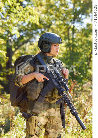 young caucasian military woman holds a gun in her hand in nature 71564529