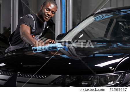 afro american man cleaning car with microfiber cloth, car detailing or valeting concept afro american man cleaning car with microfiber cloth, car detailing or valeting concept 71565657