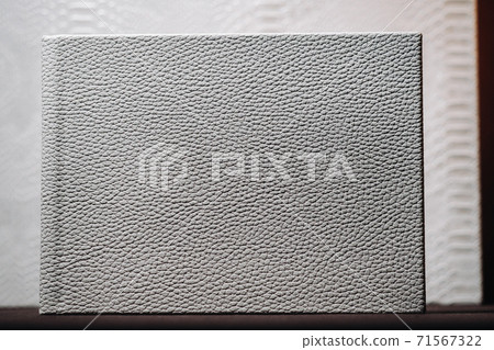 Composition of photo books in natural white leather of different sizes. The white paper on a dark background. 71567322