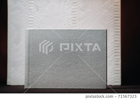 Composition of photo books in natural white leather of different sizes. The white paper on a dark background. Composition of photo books in natural white leather of different sizes. The white paper on a dark background. 71567323
