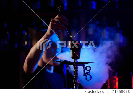 Man smoking traditional hookah pipe and exhaling smoke in hookah cafe. Man smoking traditional hookah pipe and exhaling smoke in hookah cafe. 71568038