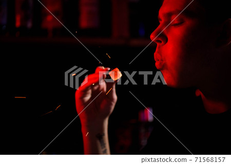 Shisha hookah, red hot coals. Man blows coals for sparks fly. 71568157