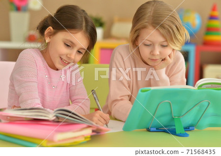 Portrait of two beautiful little girls doping homework Portrait of two beautiful little girls doping homework 71568435