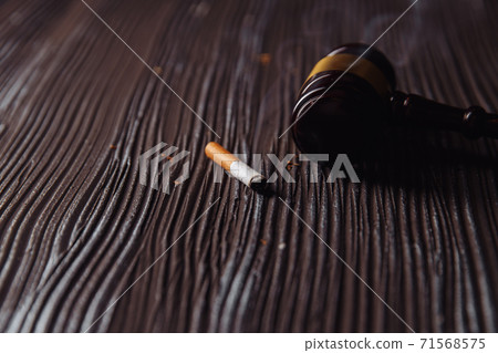 Wooden judge gavel and smoking cigarette. Dangerous habbit Wooden judge gavel and smoking cigarette. Dangerous habbit 71568575