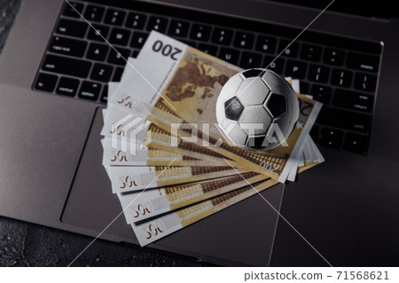 Bets, sports betting, bookmaker. Soccer ball and money on a laptop's keyboard close-up Bets, sports betting, bookmaker. Soccer ball and money on a laptop's keyboard close-up 71568621