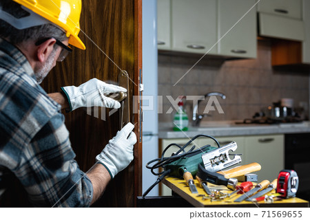 Carpenter at work repairs and installs the door lock. Carpentry. Carpenter at work repairs and installs the door lock. Carpentry. 71569655