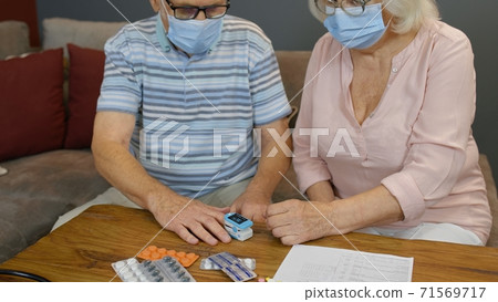Senior couple grandfather and grandmother monitoring oxygen saturation with digital pulse oximeter Senior couple grandfather and grandmother monitoring oxygen saturation with digital pulse oximeter 71569717