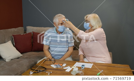 Senior couple measures temperature with contactless digital thermometer during coronavirus lockdown Senior couple measures temperature with contactless digital thermometer during coronavirus lockdown 71569719