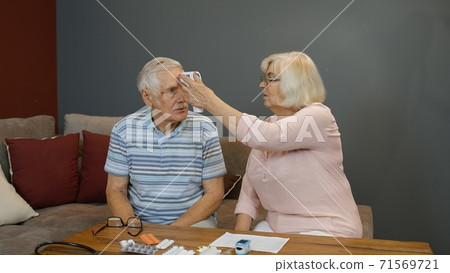 Senior couple measures temperature with contactless digital thermometer during coronavirus lockdown Senior couple measures temperature with contactless digital thermometer during coronavirus lockdown 71569721