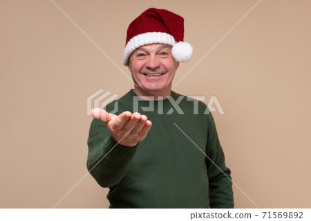 Senior hispanic man with red santa hat smiling. 71569892