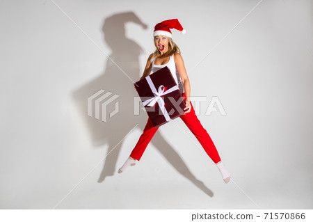 Girl jumping with red Christmas gift. 71570866