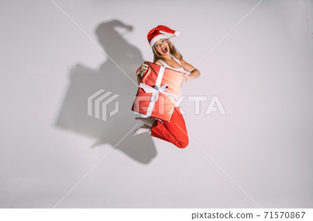 Smiling young lady jumping high with Christmas 71570867