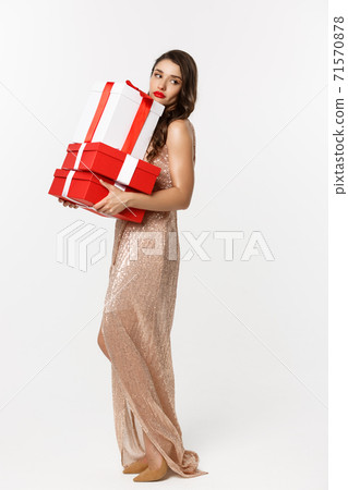 Party and celebration concept. Full-length of attractive glamour woman in elegant dress, holding Christmas gifts and looking tired, white background 71570878