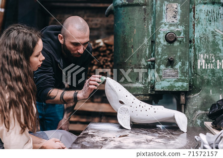 People carefully work on a ceramic whale in workshop 71572157