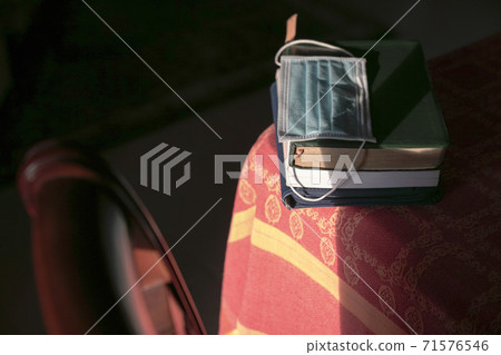 Face mask on top of stacked books on top of table 71576546