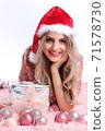 happy girl with santa hat lying between christmas ornaments 71578730