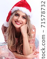 happy girl with santa hat lying between christmas ornaments 71578732