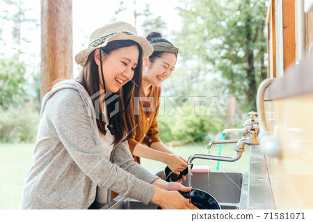 Asian woman washing dishes and utensils at campsite washing area Asian woman washing dishes and utensils at campsite washing area 71581071