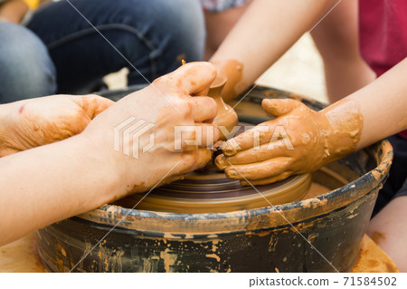 A close up view on ceramic production process on potter's wheel with children. Clay crafts with kids concept A close up view on ceramic production process on potter's wheel with children. Clay crafts with kids concept 71584502