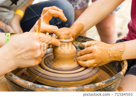 A close up view on ceramic production process on potter's wheel with children. Clay crafts with kids concept A close up view on ceramic production process on potter's wheel with children. Clay crafts with kids concept 71584503