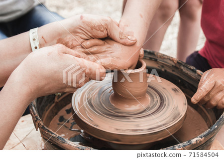 A close up view on ceramic production process on potter's wheel with children. Clay crafts with kids concept A close up view on ceramic production process on potter's wheel with children. Clay crafts with kids concept 71584504