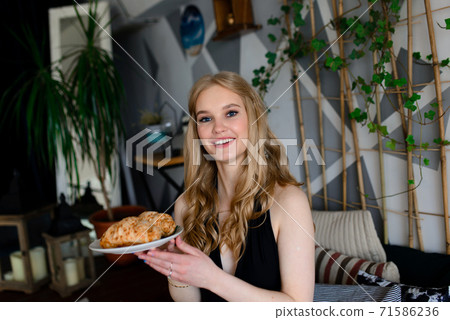 Portrait of beautiful woman in lingerie, black swimsuit with a sweet cake, croissant 71586236