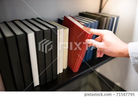 Male hand picking red book on bookshelf Male hand picking red book on bookshelf 71587795